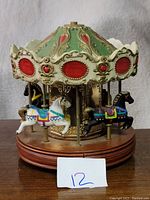 Photo of vintage Waco melody in motion carousel with detailed colored horses and green/red decorative canopy on wooden base.