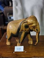 Front and side view of hand carved wooden elephant sculpture showing textured ear details and defined trunk.