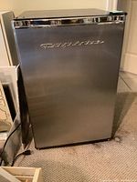 Photo of stainless steel Frigidaire compact fridge with chrome trim showing front door and logo.
