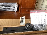 Barn door hardware box showing metal track, roller wheels, and instruction sheet inside.