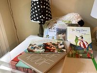 Photo showing lamp, plush lamb toy and multiple children's books on table.