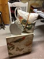 Overall view showing the chair, pillow, wall print and metal basket grouped together on a carpeted basement floor