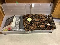 Storage tote with three different draperies including packaged Ralph Lauren blackout drapes and two other folded fabric pieces.