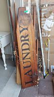 Full view of vintage wooden ironing board with LAUNDRY stencil and visible worn areas.