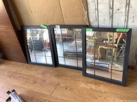 Three wood framed mirrors in window pane style, leaning against a wall on a wooden floor.