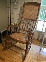 Front view of wood rocking chair with woven cane seat and back.