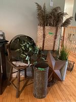 Lot contents including large round metal wall hanging with faux ivy on wooden chair, faux fish sculpture in front, metal umbrella stand with faux grass, basket backpack with pampas grass, large metal star wall hanging