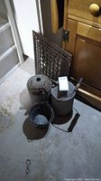 Overview of all items included: metal floor grate standing vertically, two galvanized cans and a pail on the floor.