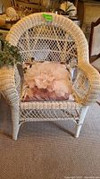White wicker armchair with floral cushion visible damage to wicker on arms and seat.