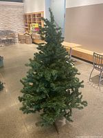 Full view of the assembled artificial Christmas tree approximately 69 inches tall, on tripod stand, indoors