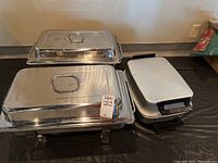 Two covered chafing dishes and one two-pan chafing dish displayed on a table