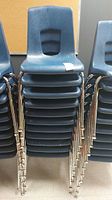 Front view of stacked blue plastic chairs showing seat design and stack height.