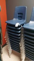 Stack of blue plastic chairs with chrome legs against wall