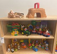 Shelf display showing the plastic toys including the playset, green tractor trailer toy, and multiple small character and animal figures