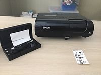 Epson EX90 projector alongside the RC laser pointer set in a black hard case on a table, note with item information visible.