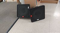 Pair of black Fender speakers with square front and red logo, placed on floor.