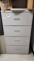 Front view of the 4-drawer gray metal filing cabinet showing recessed handles and lock on the top drawer.
