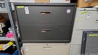 Front view of the two-drawer black metal filing cabinet showing handles and locking mechanism.