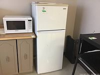 Kenmore white refrigerator and Panasonic microwave on beige cabinet.