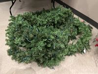 Untangled pile of artificial pine garland with visible green string lights.