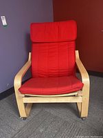 Front view of red fabric Ikea lounge chair with bentwood frame and cushion.