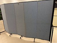 Front view of 5 gray fabric panels and metal frame on wheeled base