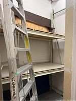 Front view of white steel shelving unit with ladder beside it