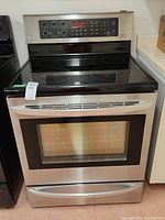 Front view of stainless steel LG electric stove with oven door, control panel, cooktop and lower drawer