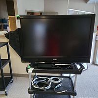 Front view of Sony Bravia 40 inch TV on a stand with remote and AV cables below