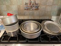 Various round baking pans stacked together, showing different sizes and shapes including deep and shallow cake pans.