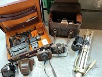 Overview of two cameras, lenses, flash, tripod, cases and accessories arranged on floor