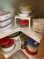 Overview image showing stacked plastic containers with lids, glass pie plates, and CorningWare bakeware with Blue Cornflower pattern.