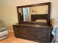 Front view of the dresser with attached mirror showing carved wooden drawers and metal handles.