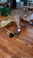 Photo showing full fireplace tool set on hardwood floor including ash bucket, brush and pan, bellows, and fireguard.