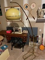 Full view of floor lamp showing curved metal frame, base, cord, shade and surrounding items.