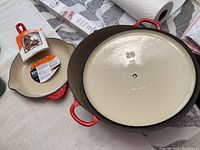 Top view of red enameled cast iron 28 cm Dutch oven without lid alongside 23 cm skillet