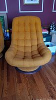 Front view of one orange swivel chair showing tufted grid-pattern upholstery and overall shape