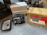 Overall view of projector with original box and styrofoam packaging on concrete basement floor.