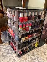Full view of the rotating acrylic nail polish storage cabinet filled with assorted nail polishes visible on all four shelves