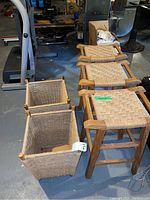 View of three wooden stools with woven twine seats and two square woven twine baskets, set on basement floor.