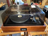 Front view of entire turntable showing walnut-veneer base and smoked dust cover