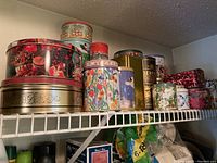 Multiple decorative metal tins on shelving, various sizes and designs