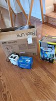 APC Back-UPS unit in box, power transformers in box and one outside box and clothes steamer boxed and standing