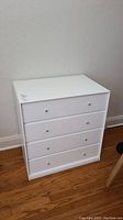 Front view of white 4-drawer chest dresser with round metal knobs