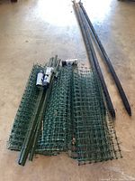 Poles, mesh rolls, stakes, and spray paint visible on concrete floor