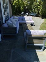 Angled view of the full patio set showing three chairs, two two-seater benches, and coffee table on stone patio