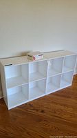 Long white cube shelf with eight compartments against wall