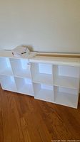 Two white cube storage shelving units, one 3x2 cubes and one 2x2 cubes, front view