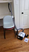 Vacuum on floor next to two stacked plastic chairs, hoses attached
