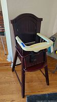Full view of the wooden high chair with white plastic tray and black seat belt. Shows overall condition and design.